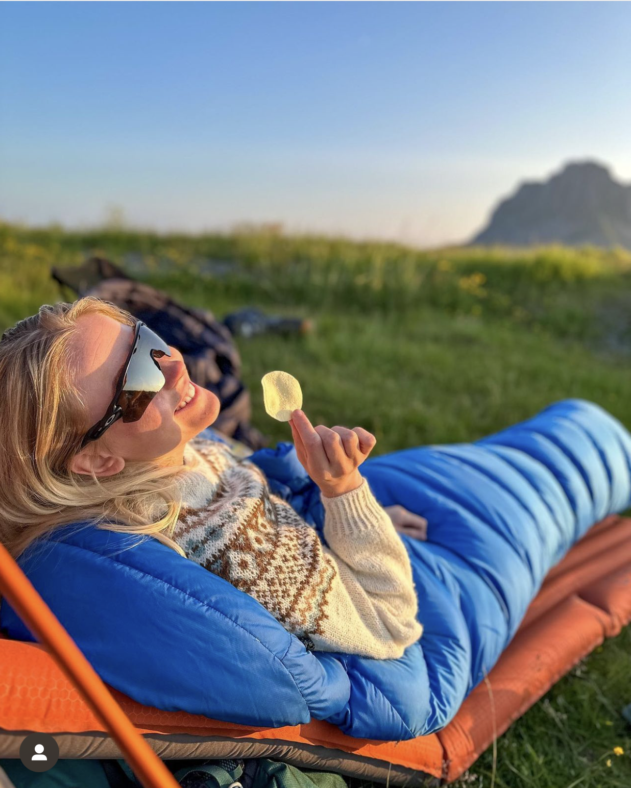 En person som sitter i naturen og spiser potetgull