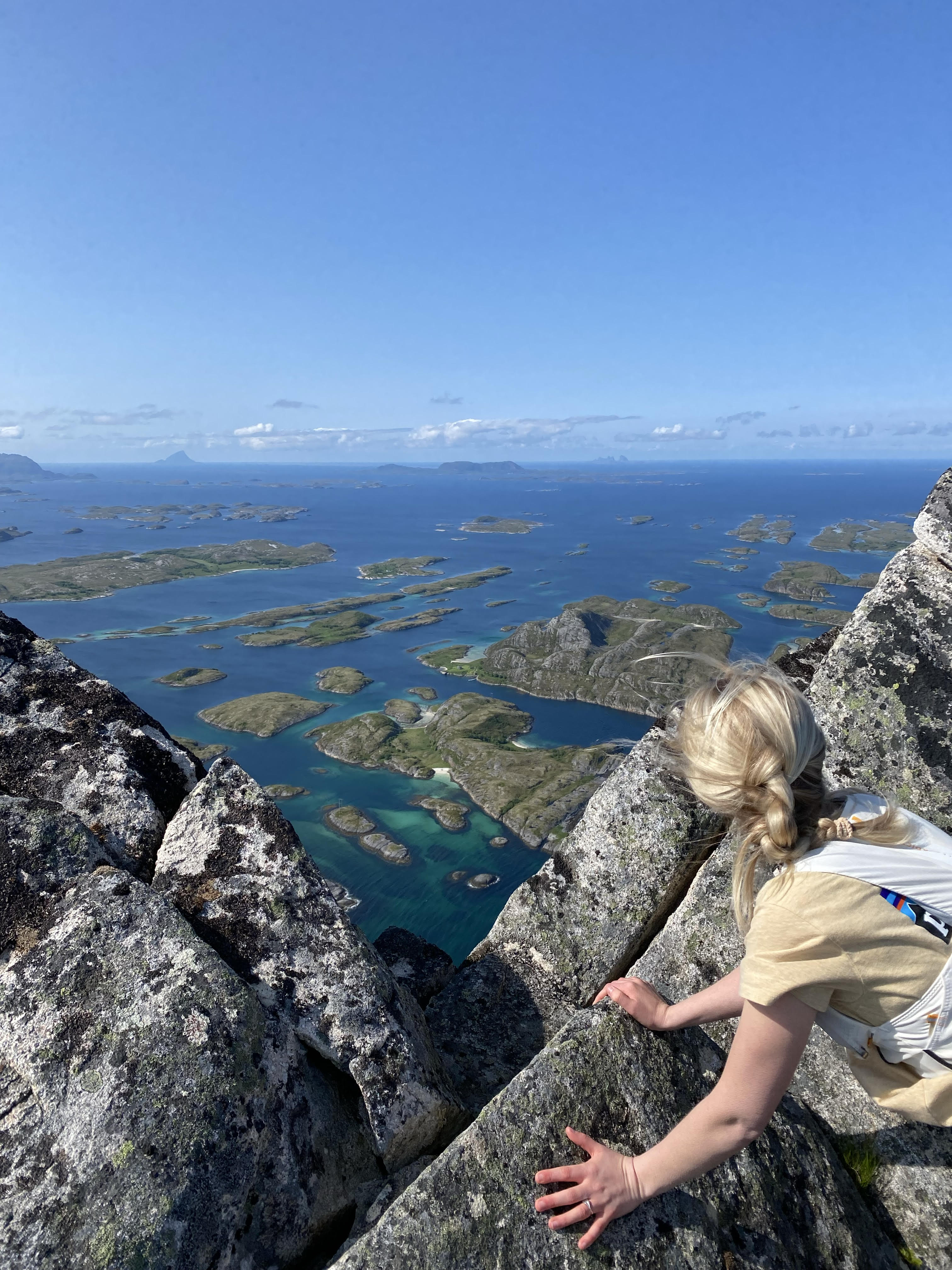 En person som ligger på mage for å se på utsikten på kanten av et fjell