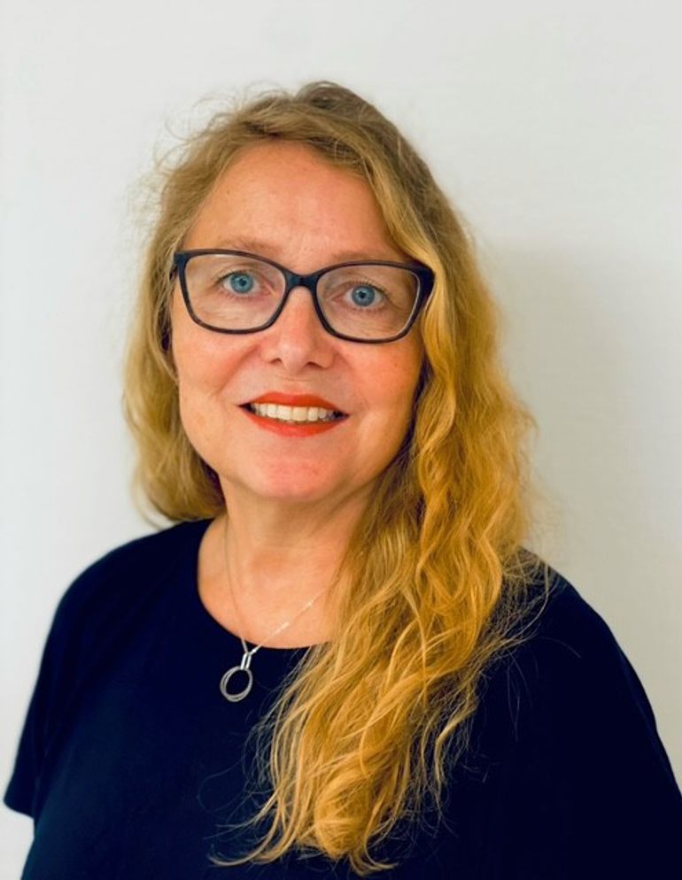 En kvinne med langt blondt hår med briller og svart skjorte