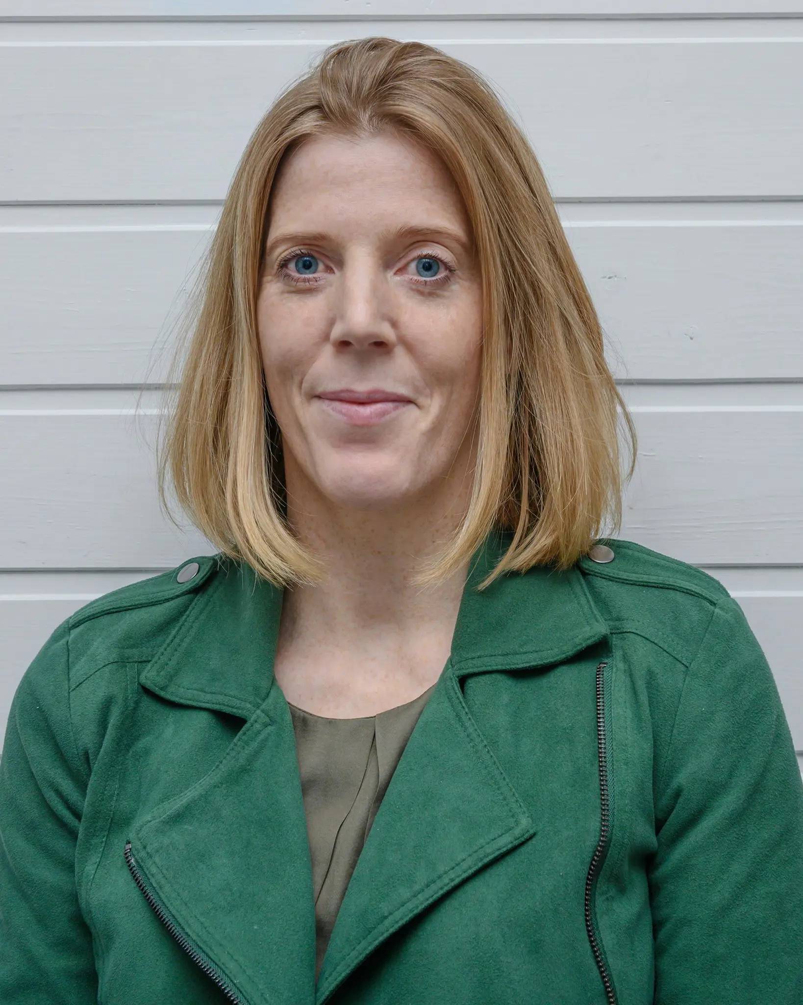 Dame med rødblondt hår og grønn jakke