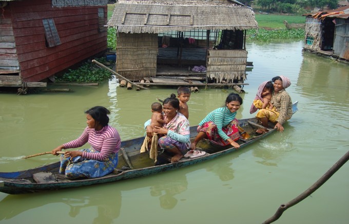Kvinner og barn padler i en kano i Kambodsja