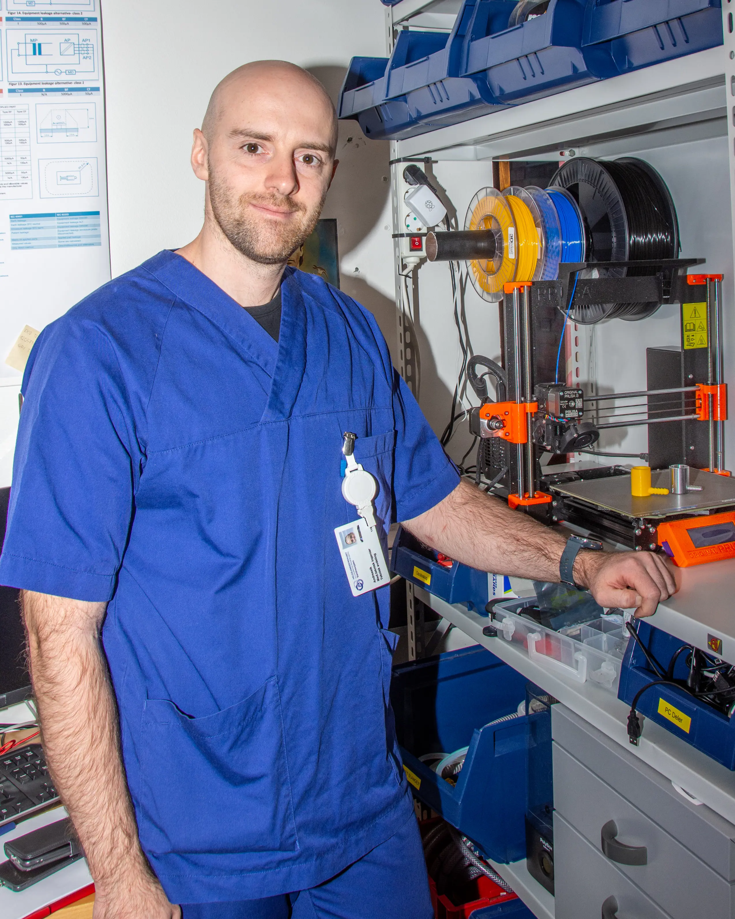 Bilde av ung mann i blålkjeledress foran-3Dprintmaskin