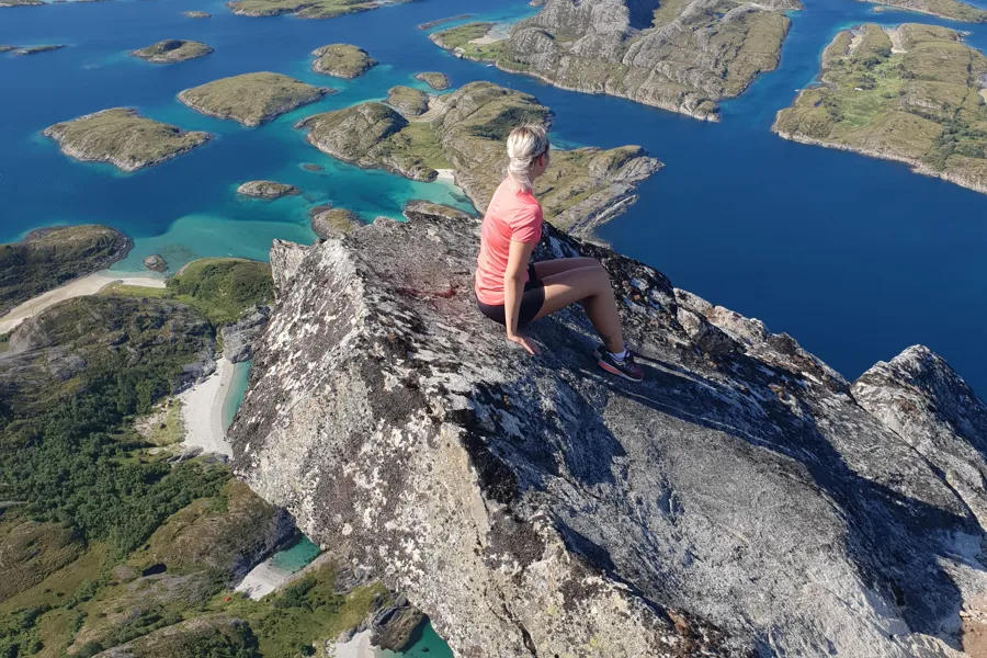 En person som sitter på en stein med utsikt over en vannmasse