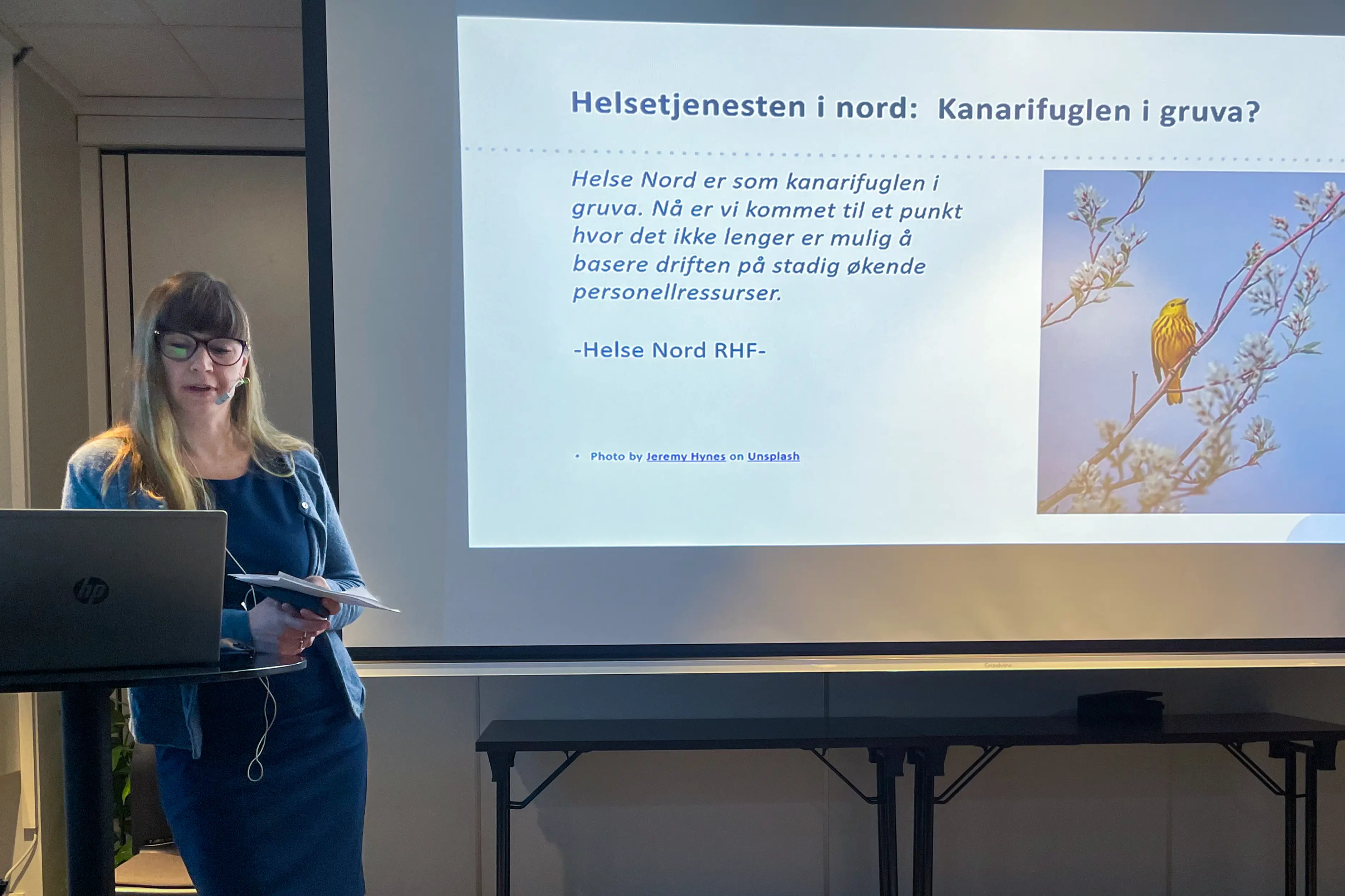 Dame støtter seg til et høyt bord mens hun prater.