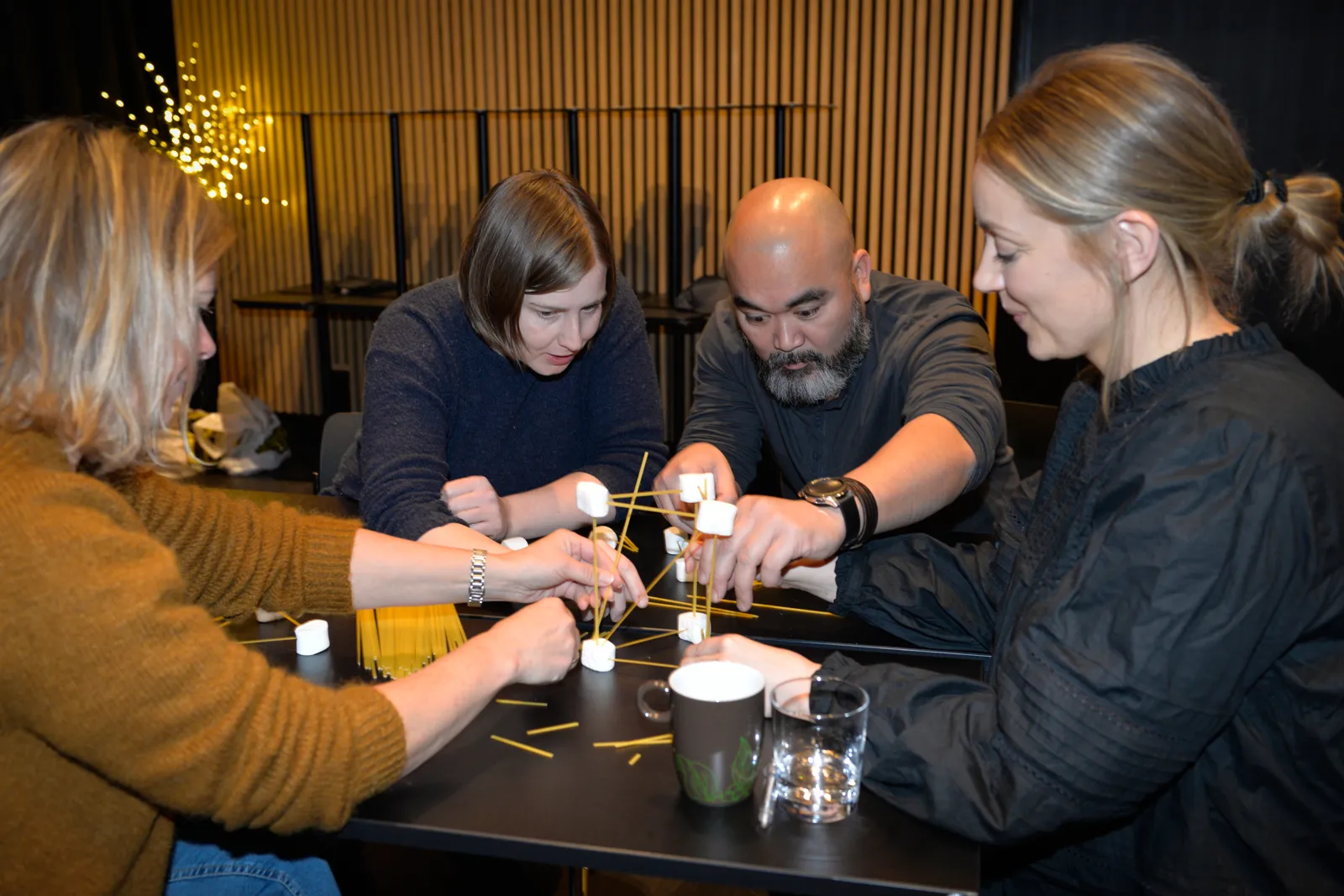 Fire personer sitter konsentrert rundt et bord