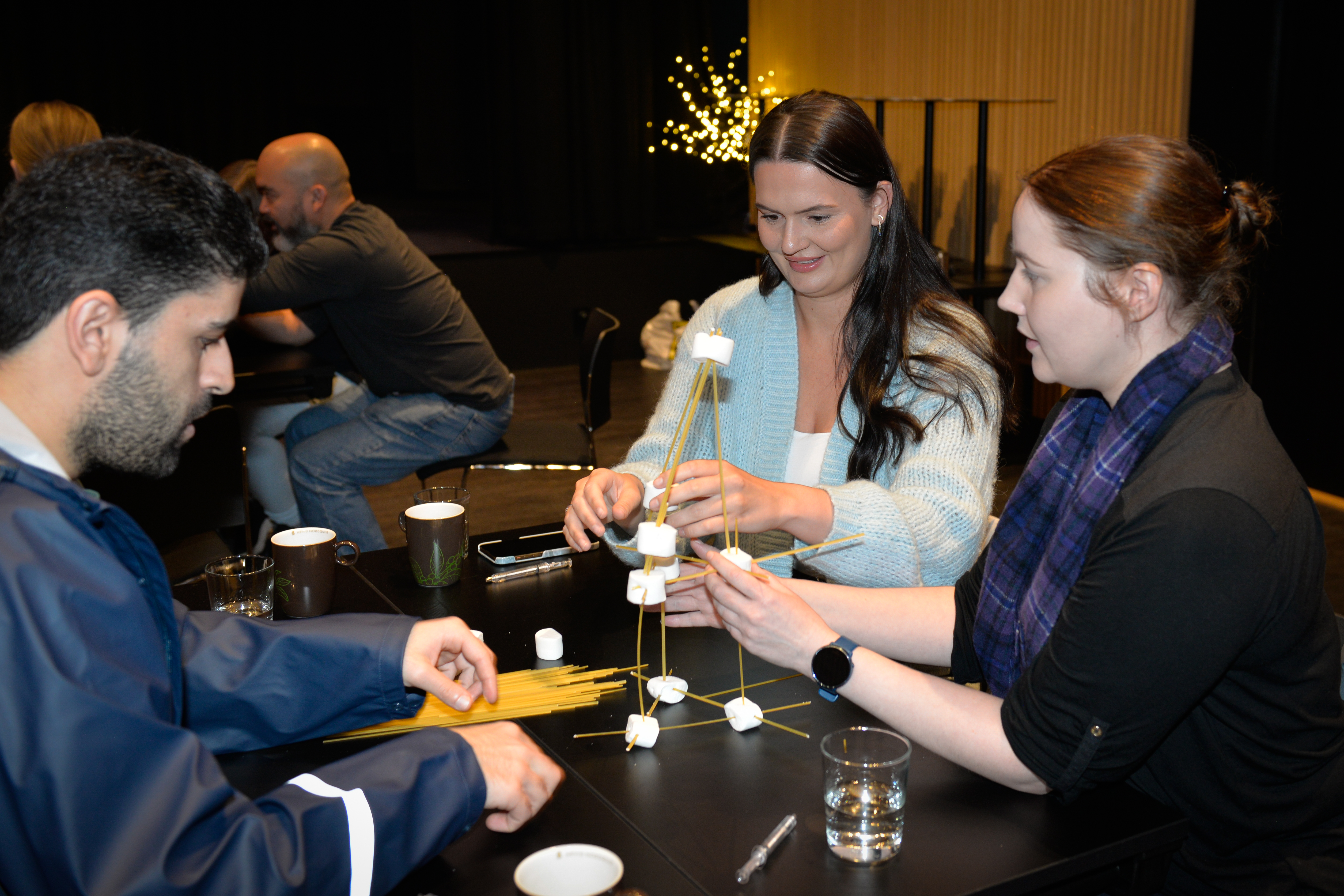 Tre personer samarbeider om å bygge et tårn på 80 cm