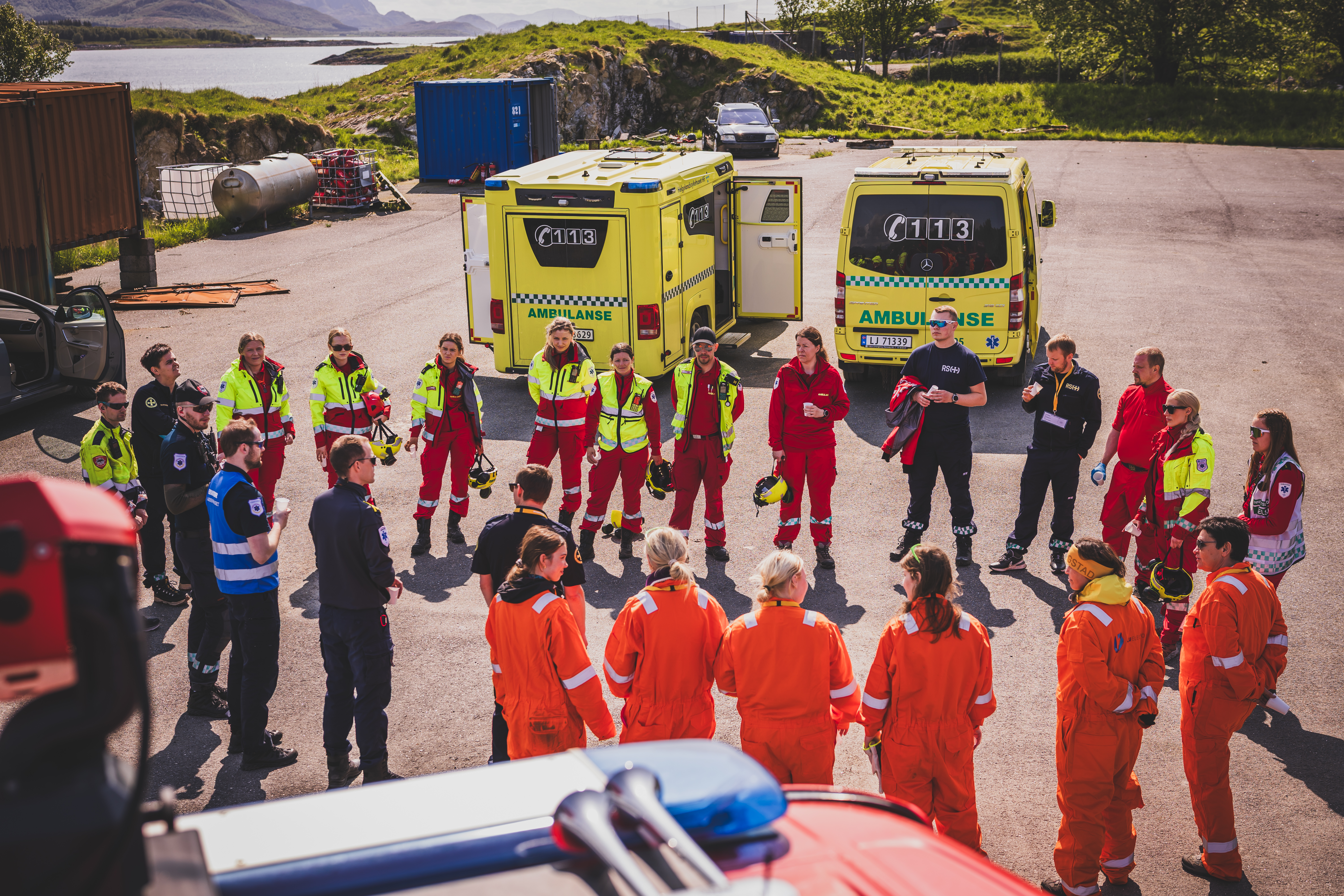 Mange personer fra blålysetatene står i en stor sirkel og snakker