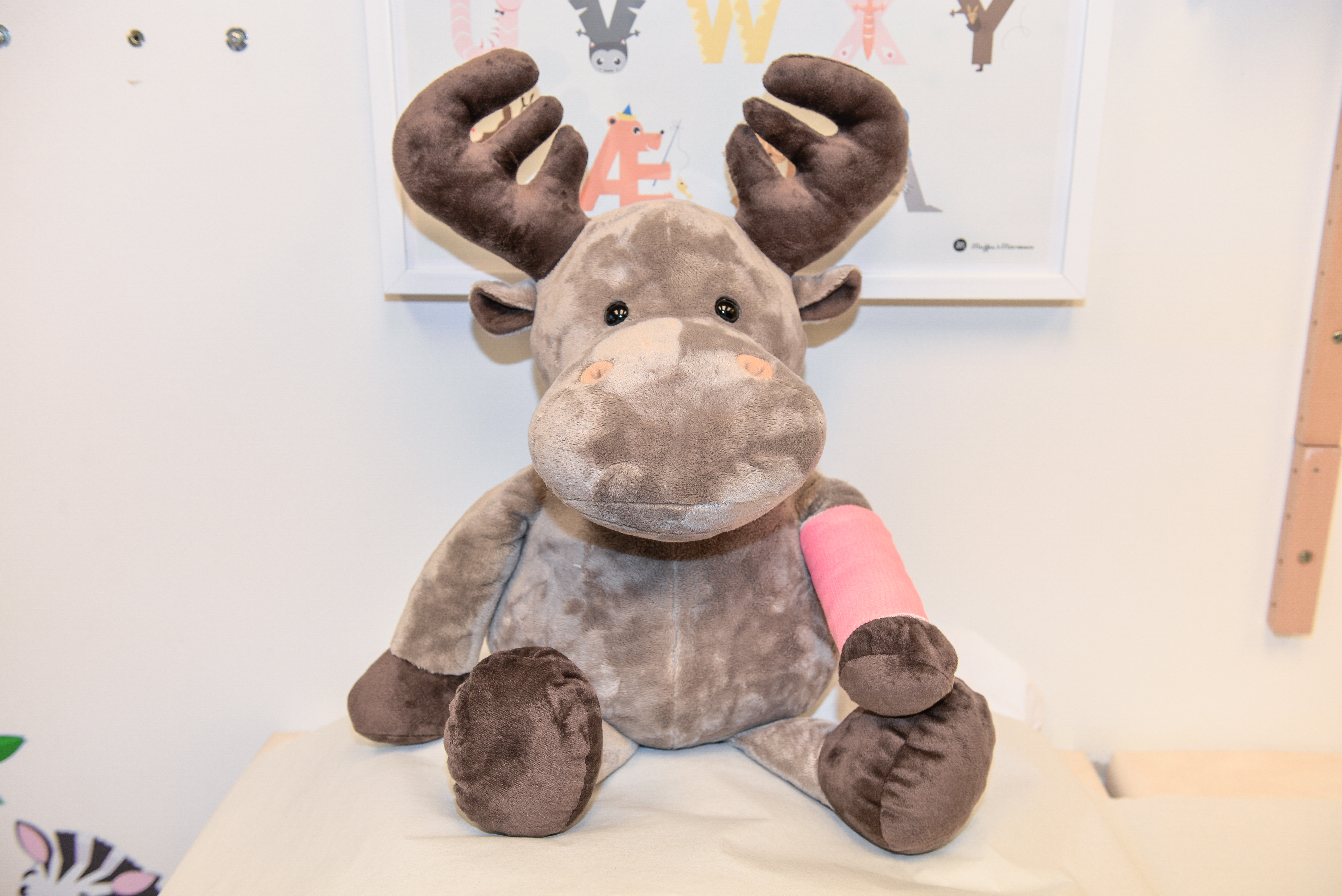 Sykehusets maskot, Elgen Eik, sitter på ei undersøkelsesseng med gips på den ene armen