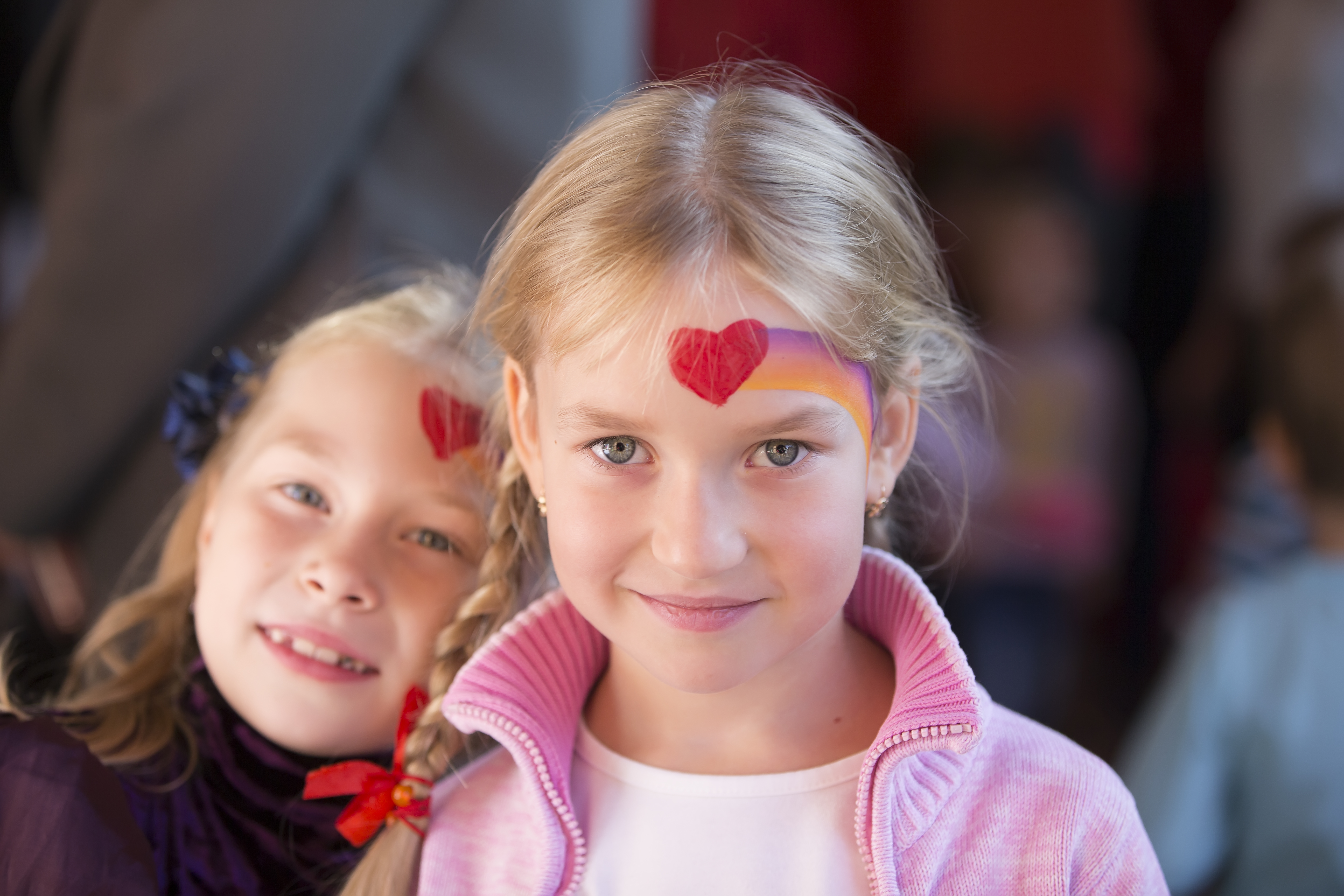 To jenter med hvert sitt påmalte hjerte i panna
