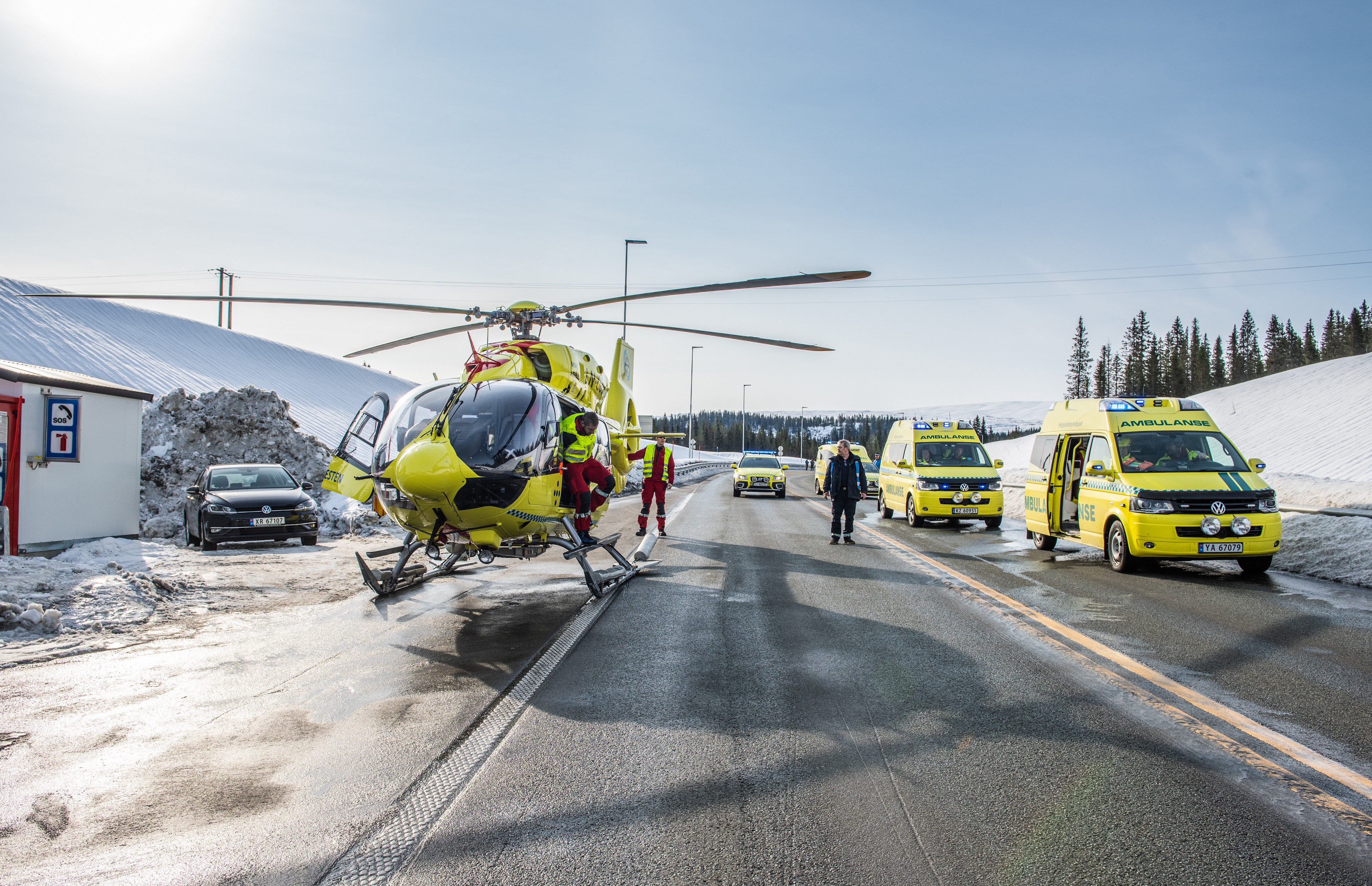 A group of emergency vehicles on a road with snow on the ground
