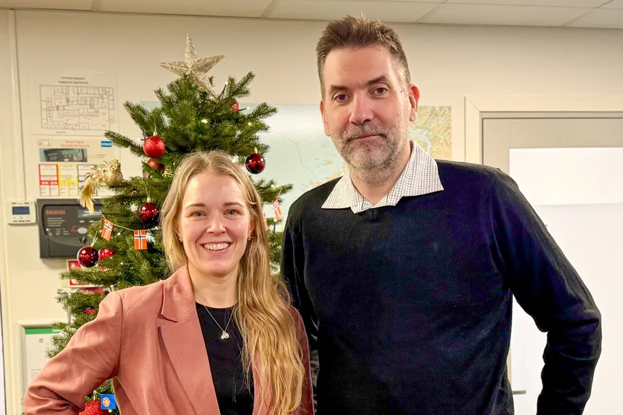 En mann og en kvinne står ved siden av et juletre